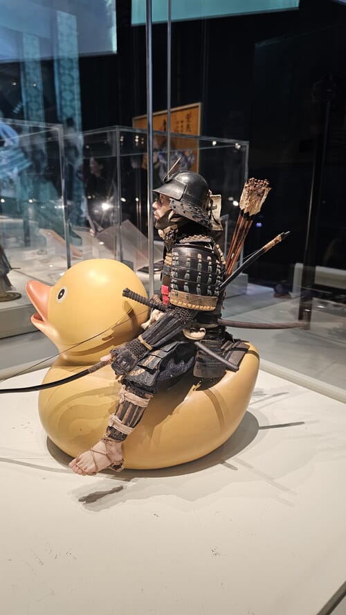Artwork by Noguchi Tetsuya depicting a samurai figure holding an inflatable rubber duck